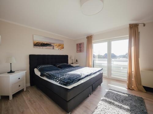 a bedroom with a bed and a large window at Beachcomber House B in Friedrichskoog