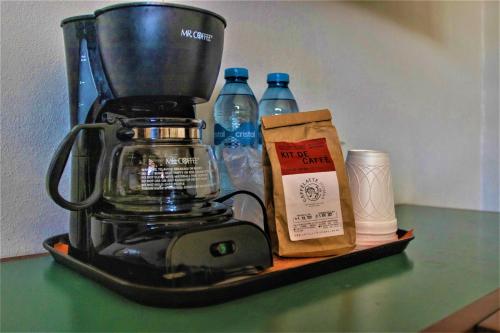 a black blender on a shelf with bottles of water at Hotel Caribe Merida Yucatan in Mérida
