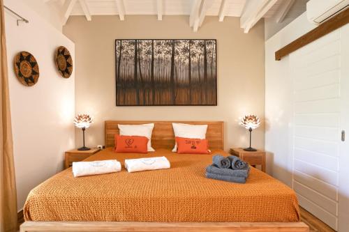 a bedroom with a bed with orange sheets and red pillows at Les Galets Sxm in Saint Martin