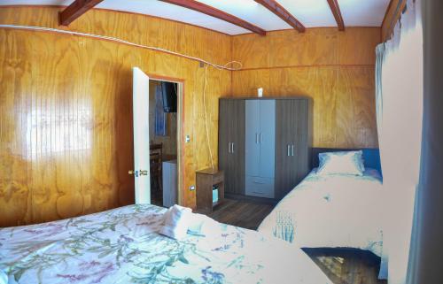 a bedroom with a bed and wooden walls at Entre Montañas in Hornopiren