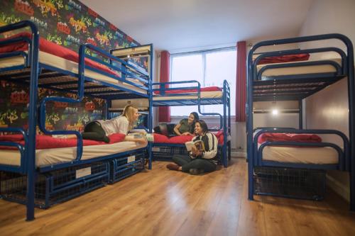 three people sitting on the floor in a room with bunk beds at Abigail's Hostel in Dublin