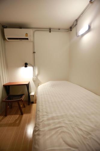 a small bedroom with a bed and a table at My Home Hostel in Ban Na Kham