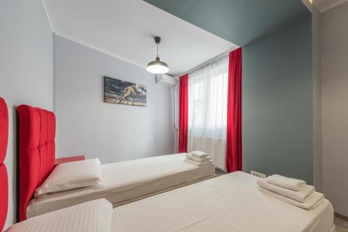 a bedroom with two beds and red curtains at Royal Accommodation in Bucharest