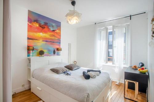 um quarto com uma cama com um quadro na parede em L'Aparté HYPER CENTRE LUMINEUX em Lorient