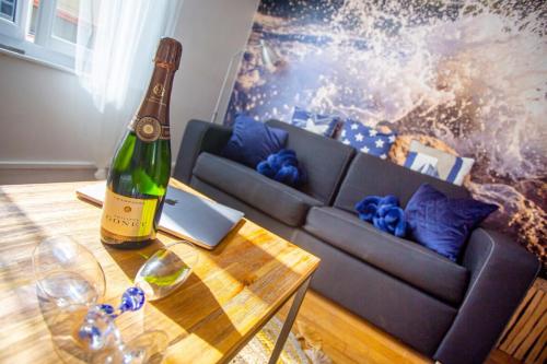 - une bouteille de vin assise sur une table à côté d'un canapé dans l'établissement L'Aparté HYPER CENTRE LUMINEUX, à Lorient