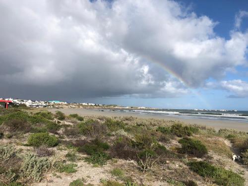 a rainbow in the sky over a beach at Die Pomphuisie in Paternoster