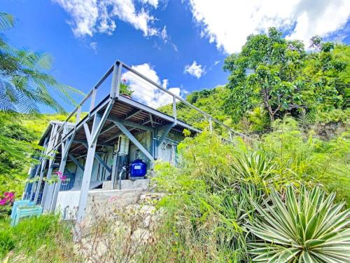 a blue house on the side of a hill at Aquamarine, private room in Villa Casa Blue pool sea view in Koolbaai