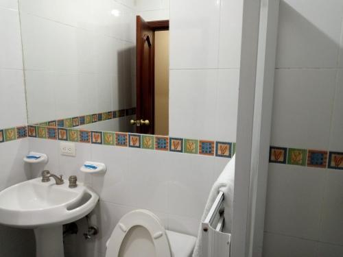 y baño con aseo y lavamanos. en Hostal EL CALLEJÓN, en Ibarra