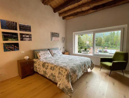 1 dormitorio con cama, ventana y silla en Casa Alpha en Vittorio Veneto