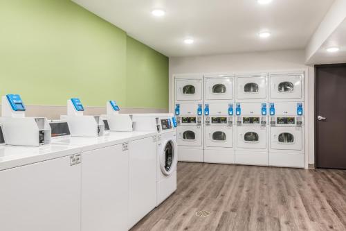 a laundry room with white washers and dryers at WoodSpring Suites Charlotte - University Research Park in Charlotte