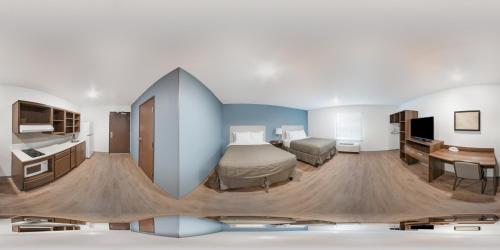 Habitación de hotel con cama, escritorio y TV. en WoodSpring Suites Charlotte - University Research Park, en Charlotte