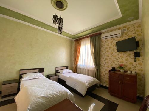 1 dormitorio con 2 camas y TV en la pared en KangAr guest house, en Ereván