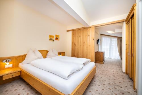 a bedroom with a large bed with white sheets at Haus am Hammerrain in Flachau