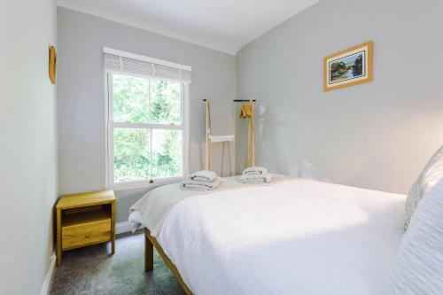 a white bedroom with a bed and a window at Fisherman's Cottage in Chester