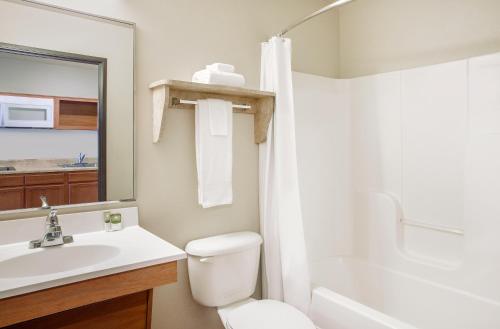 La salle de bains est pourvue d'un lavabo, de toilettes et d'une douche. dans l'établissement WoodSpring Suites Manassas Battlefield Park I-66, à Manassas