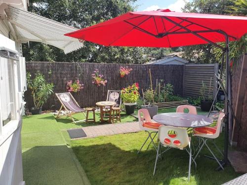 une terrasse avec un parasol rouge, une table et des chaises dans l'établissement Chalet Cosy, à Audenge