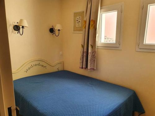 une chambre avec un lit bleu et deux fenêtres dans l'établissement Appartement 4 ou 5 pers Vue Mer Climatisé Golfe de St Tropez Grimaud Les Restanques, à Grimaud