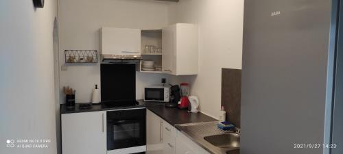 - une petite cuisine avec des armoires blanches et des appareils noirs dans l'établissement Maison indépendante près de Valenciennes climatisé ,wifi , parking privé, à Hérin