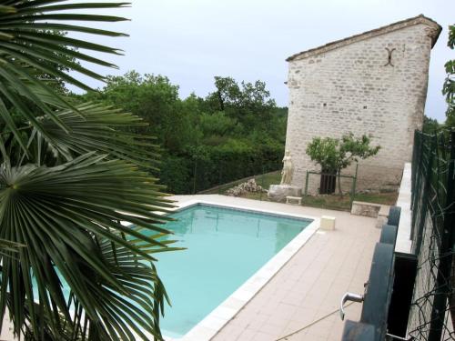 une piscine devant un bâtiment en briques dans l'établissement Maison au calme à la campagne dans le Quercy avec piscine et spa, à Bouloc