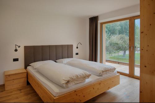 a bedroom with a bed and a large window at Appartments Lindenhof in Riscone