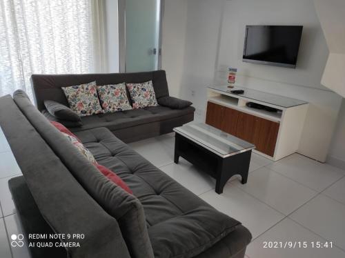 a living room with a couch and a tv at Confortável Duplex a 100 Metros da Praia in Porto Seguro