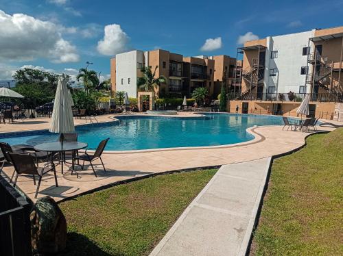 - une piscine avec une table, des chaises et un parasol dans l'établissement Apartasol, Eje cafetero Reservas de la Colina 104B, à La Tebaida