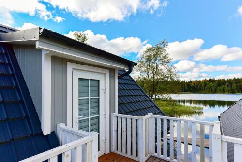 a house with a porch with a fence and a lake at Namelis ant vandens "Giliaus namelis" in Tytuvėnai