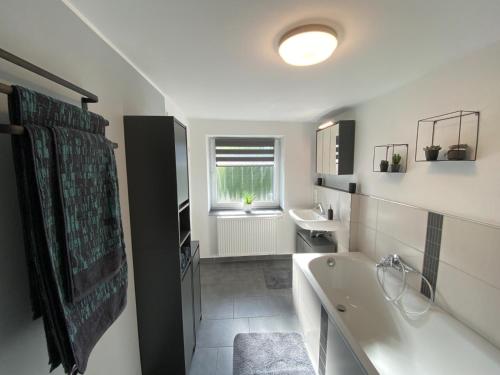 een badkamer met een bad en een wastafel bij Eifel-Ferienhaus Landblick in Hürtgenwald