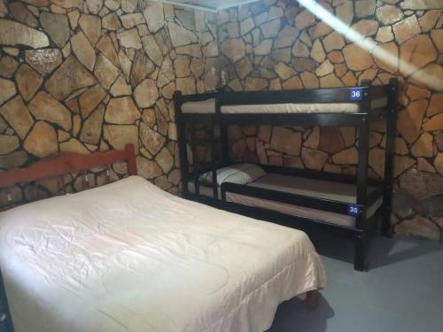 a room with a bed and a stone wall at Recanto da Iara in Arraial do Cabo
