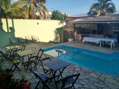 - une piscine avec des chaises et des tables à côté d'une maison dans l'établissement Recanto da Iara, à Arraial do Cabo