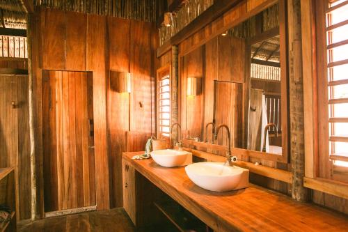 two sinks in a bathroom with wooden walls at Vila Beijú BARRINHA - Frente Mar! in Barrinha