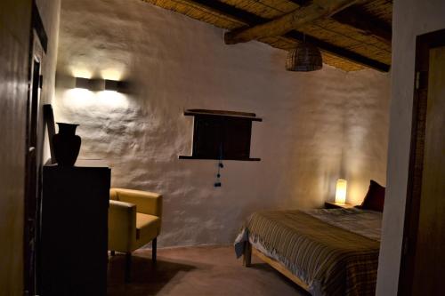 a bedroom with a bed and a chair in a room at Cabañas Sixilera in Huacalera