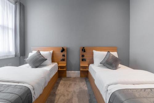 two beds in a room with white walls at Gainsborough Hotel in London