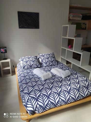 um quarto com uma cama com lençóis azuis e brancos em le studio de la plage em Trouville-sur-Mer