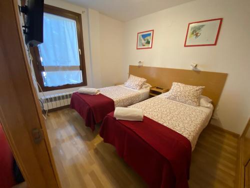 - 2 lits dans une chambre avec fenêtre dans l'établissement Apartamento Formigal - Sallent de Gállego, à Sallent de Gállego