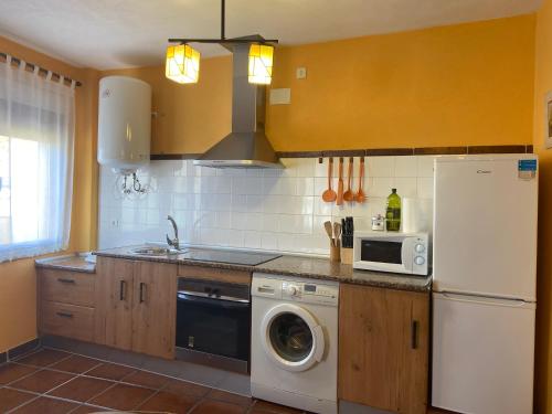 a kitchen with a white refrigerator and a washing machine at El Abigero in La Fregeneda