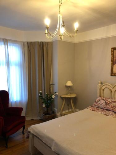 a bedroom with a bed and a chair and a chandelier at Casa Amor in Great Yarmouth
