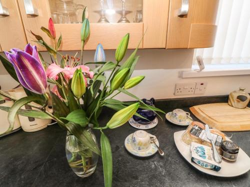 a vase of flowers sitting on a kitchen counter with plates at Two Threes in Saint Hilary