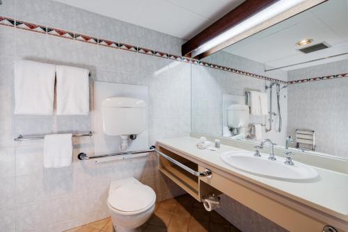 La salle de bains est pourvue d'un lavabo, de toilettes et d'un miroir. dans l'établissement Adelaide Inn, à Adélaïde