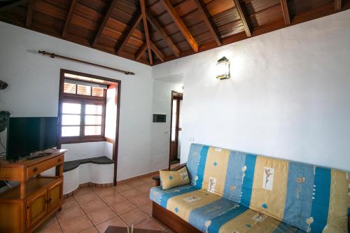 a living room with a blue couch and a television at Casas los Alisios II in Los Quemados