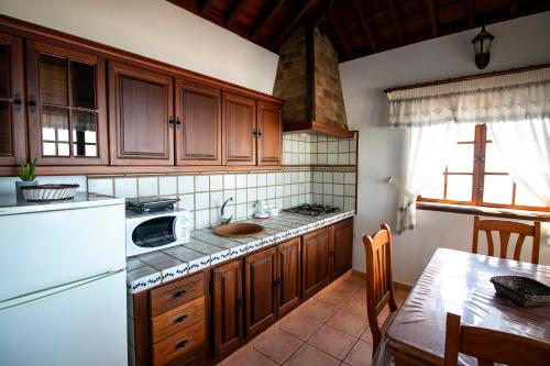 a kitchen with wooden cabinets and a white refrigerator at Casas los Alisios II in Los Quemados