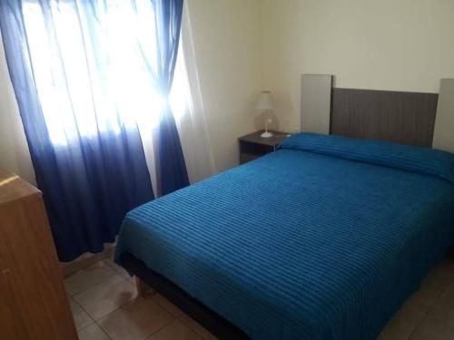 Un dormitorio con una cama azul y una ventana en CABAÑAS SOL Y LUNA en San Rafael