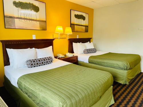 two beds in a hotel room with yellow walls at Red Carpet Inn Duncannon in New Buffalo