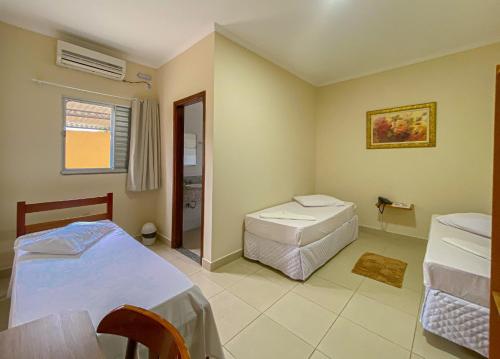 um quarto com 2 camas, uma mesa e uma janela em Graal Inn Queluz em Queluz