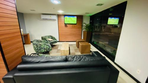 a living room with a black leather couch and a fishtank at Hotel Italia Beach in Natal