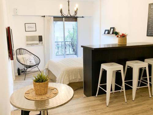 Sala de estar con cama, mesa y taburetes en HEART OF RECOLETA - STUDIO 3 pax. TEMPORARYAPARTMENTSBA en Buenos Aires