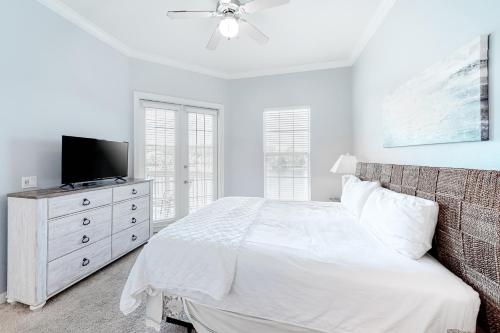 a white bedroom with a bed and a tv at Crystal Cove 2223 in Destin