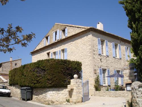 una grande casa in pietra con una siepe di fronte di Logis Auberge De Tavel a Tavel