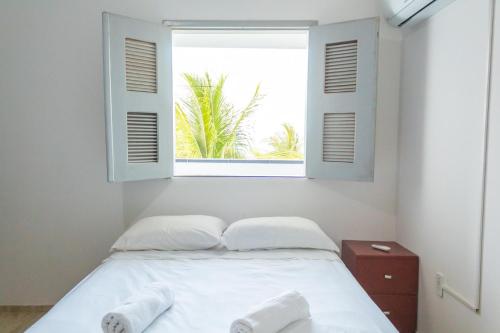 a bedroom with a bed with white sheets and a window at Vista mar Preá - Praia do Preá in Acaraú