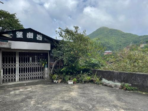 a building with a gate with mountains in the background at Wangyuku B&B in Jiufen